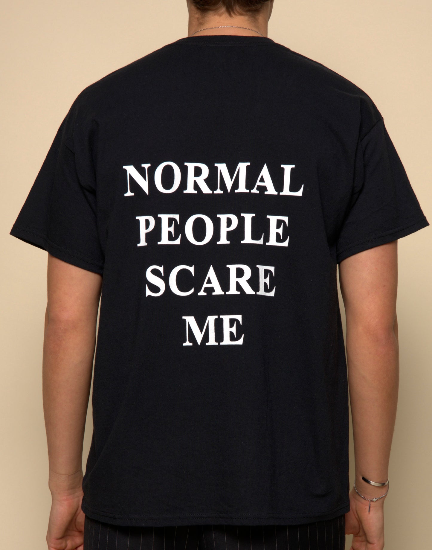normal people scare me t-shirt black. By FRASED. Unisex heavy cotton tee with a crew neckline and graphic screen print, made from 100% cotton, featuring a classic fit and tear-away label for comfort.