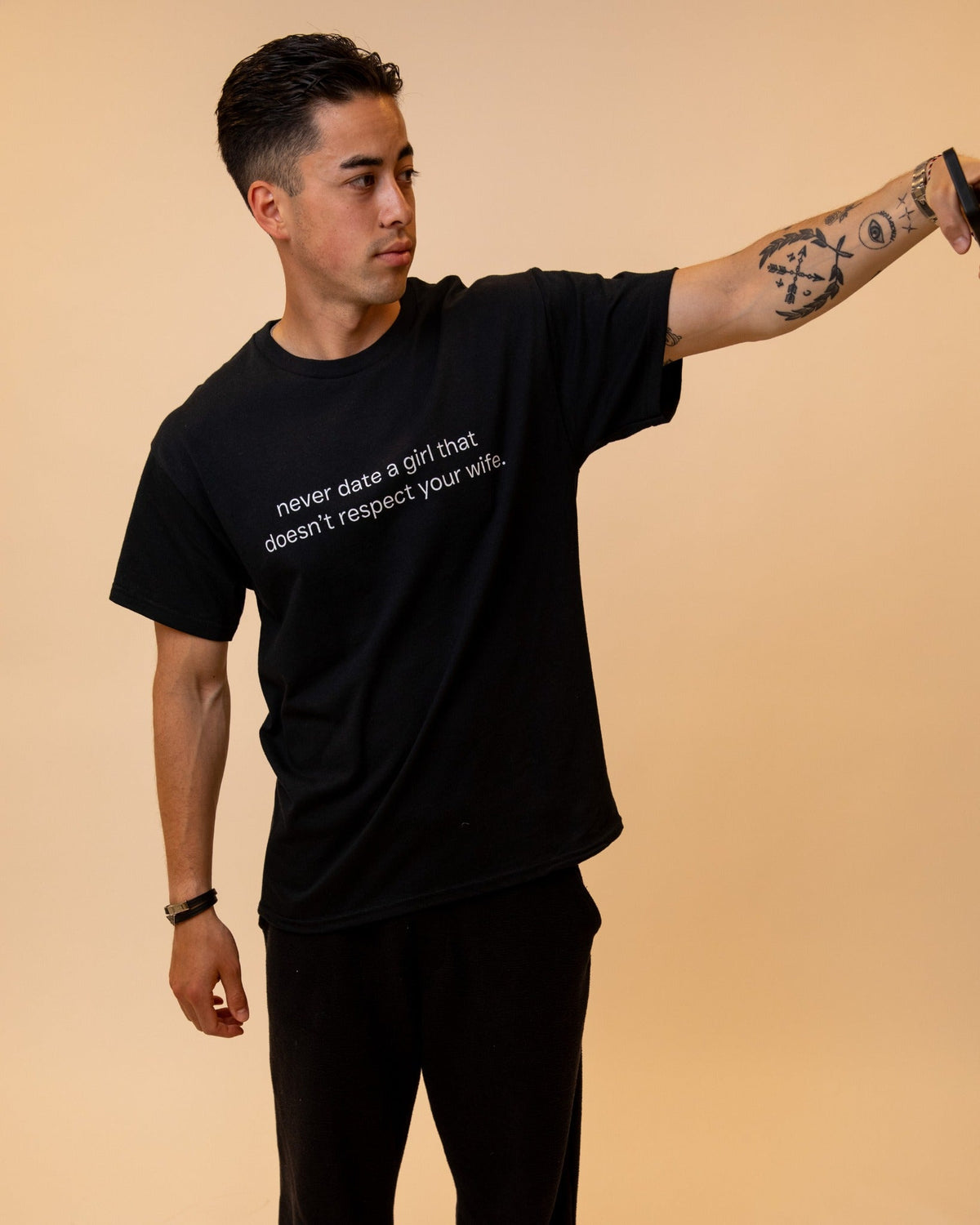 Person wearing a black FRASED classic tee with a white printed statement
