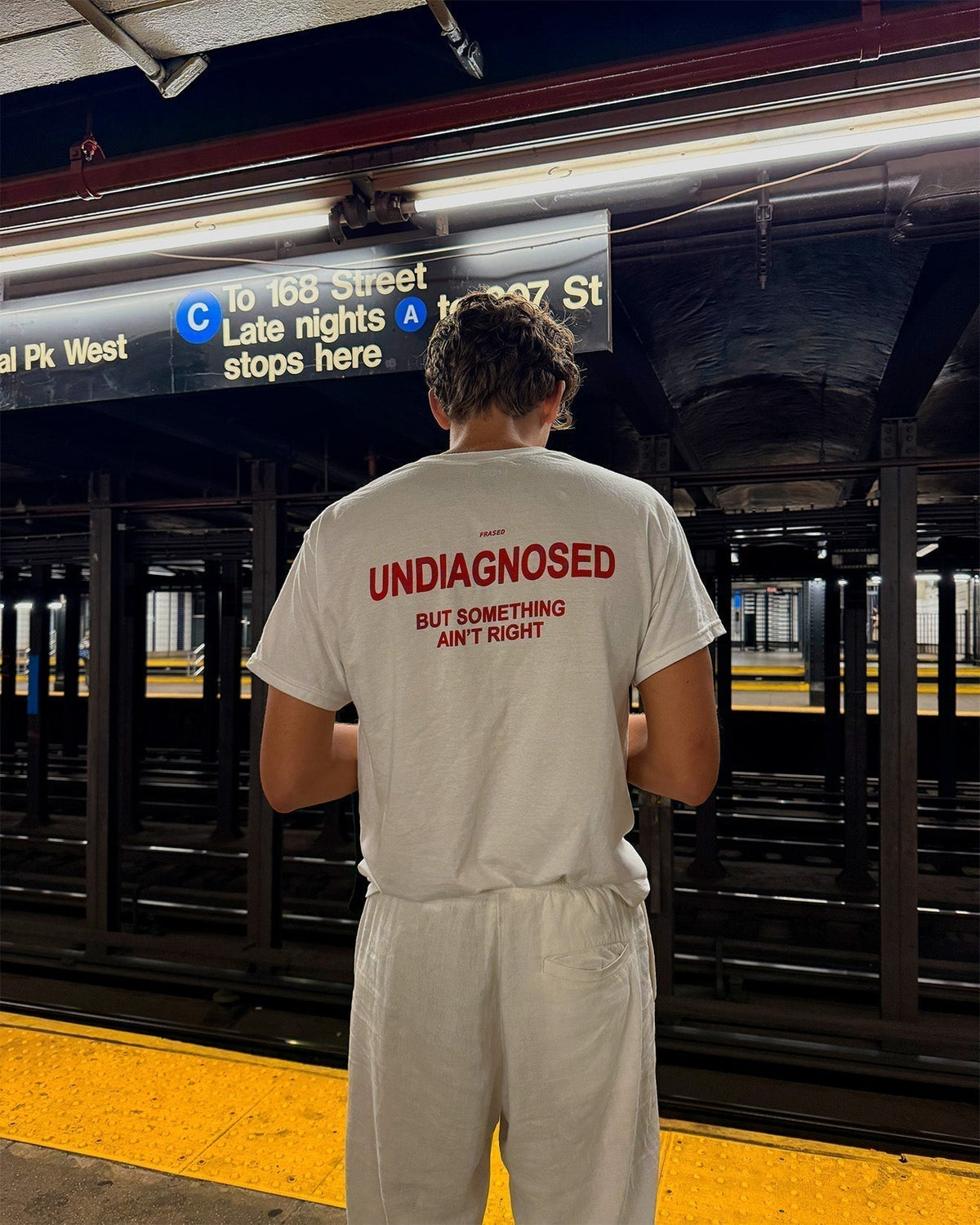 FRASED Undiagnosed But Something Ain't Right white tee worn on a subway platform