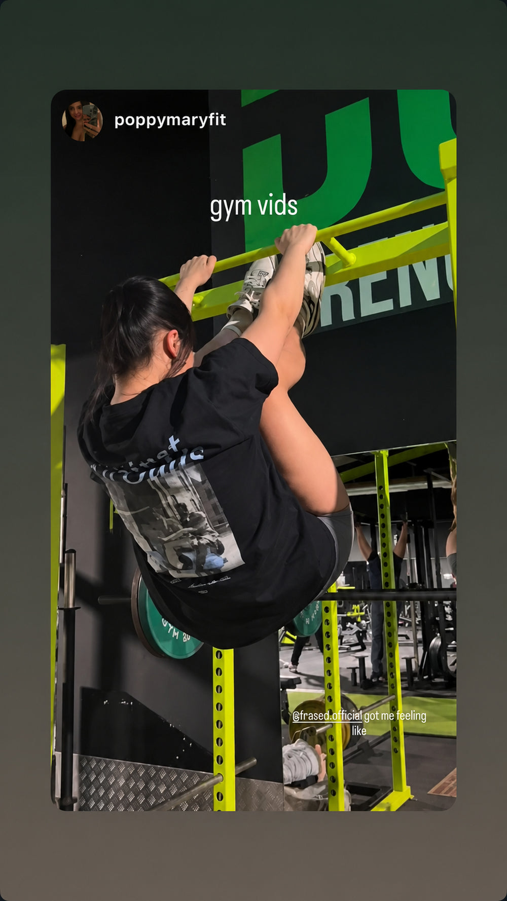 Person træner i fitnesscenter iført sort FRASED T-shirt med grafisk 'Against All Odds'-rygtryk.