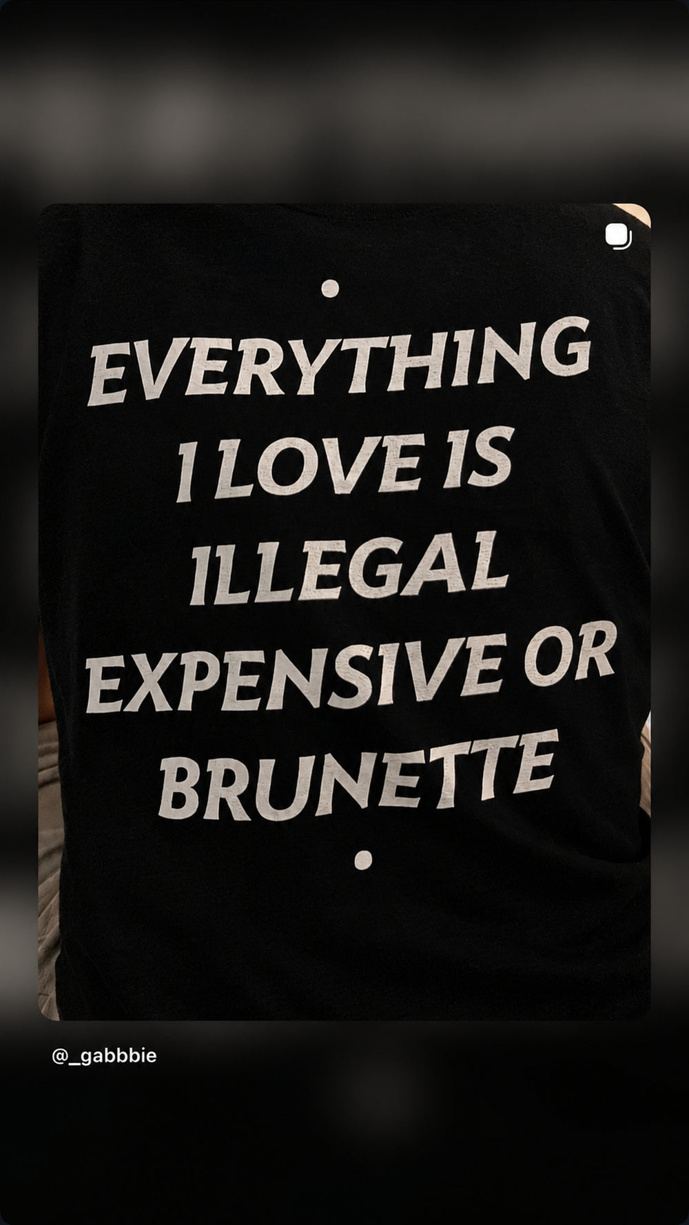 Nærbillede af ryggen på sort EVERYTHING I LOVE IS ILLEGAL, EXPENSIVE OR BRUNETTE T-shirt.