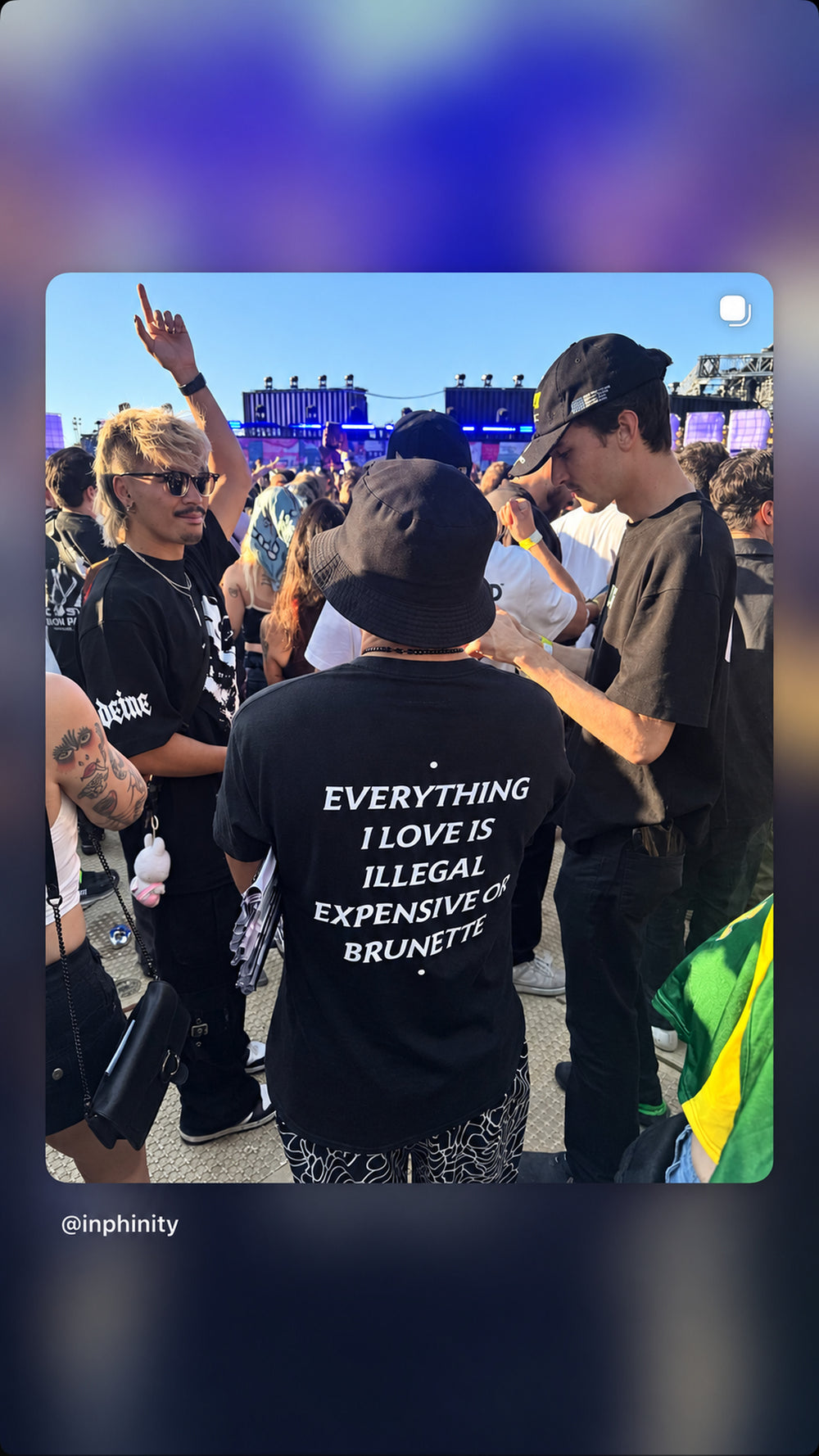 Person i sort EVERYTHING I LOVE IS ILLEGAL, EXPENSIVE OR BRUNETTE T-shirt blandt festivalgæster.