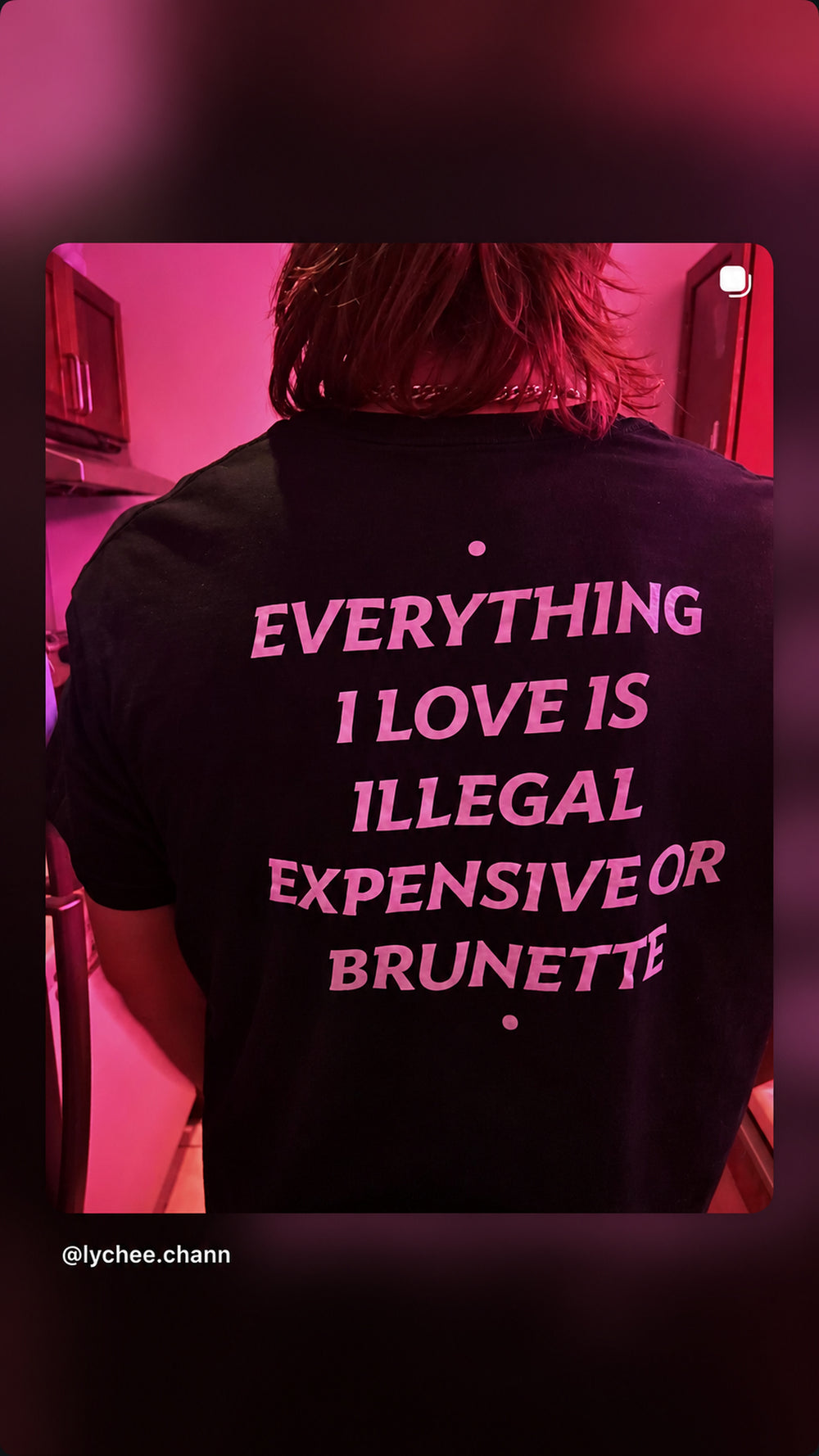 Nærbillede af sort EVERYTHING I LOVE IS ILLEGAL, EXPENSIVE OR BRUNETTE T-shirt i pink lys.