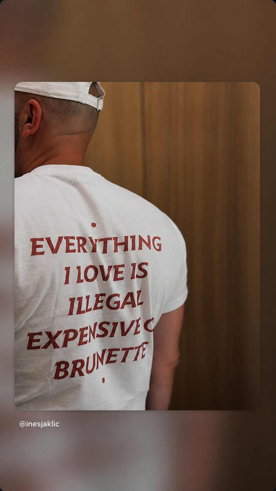 Mand i hvid EVERYTHING I LOVE IS ILLEGAL, EXPENSIVE OR BRUNETTE T-shirt og kasket set bagfra.