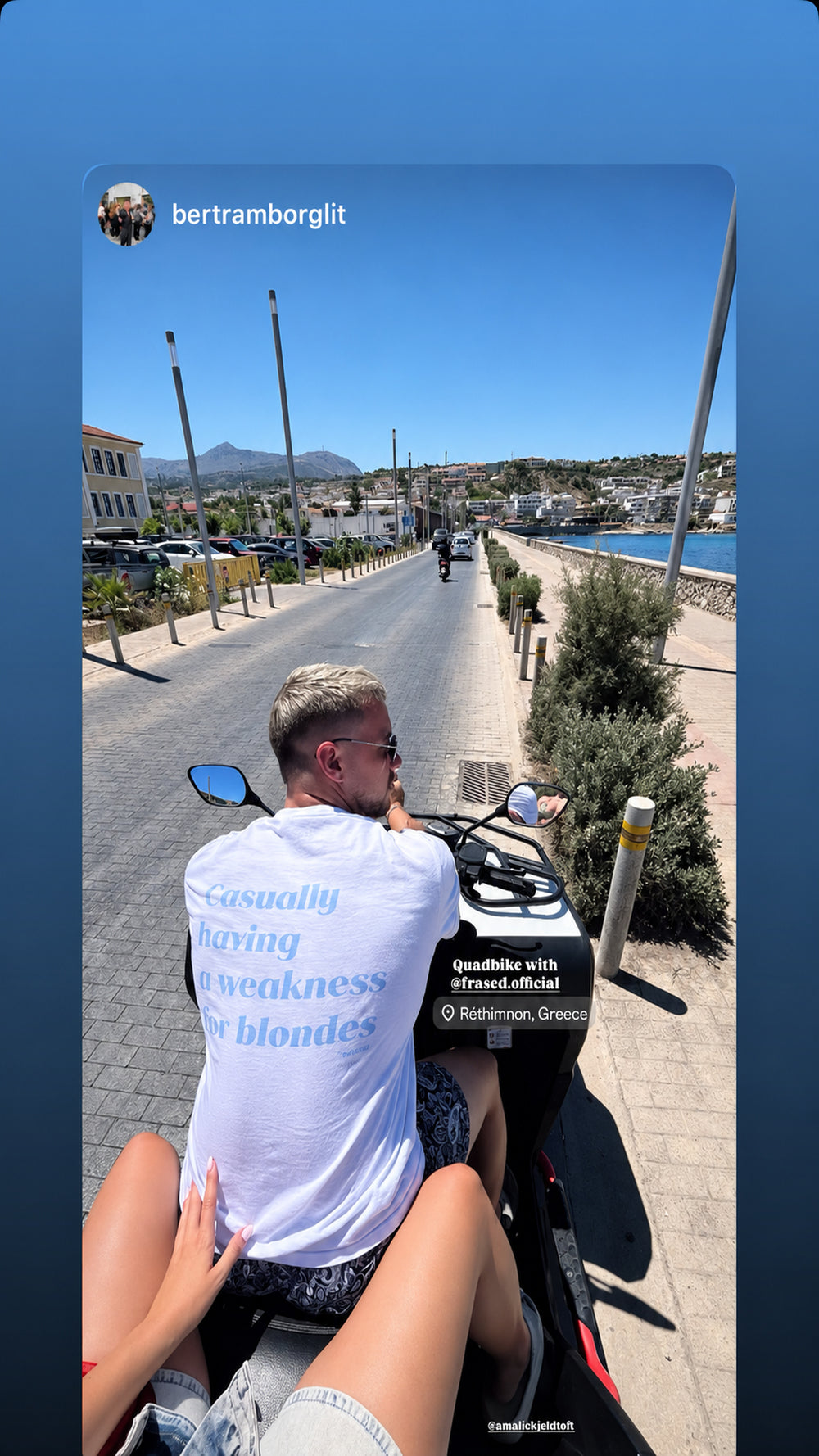 Mand på quadbike ved kysten iført hvid FRASED T-shirt med lyseblåt 'Casually having a weakness for blondes'-rygtryk.