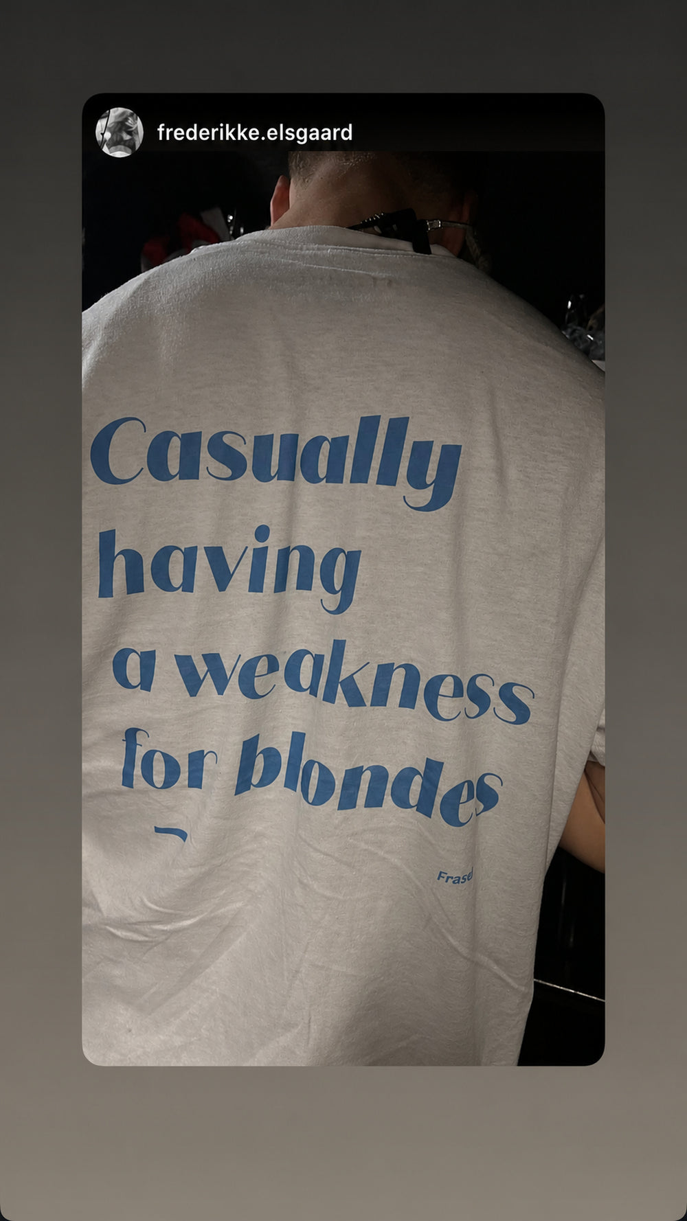 Nærbillede af ryggen på hvid FRASED T-shirt med lyseblåt 'Casually having a weakness for blondes'-tryk.
