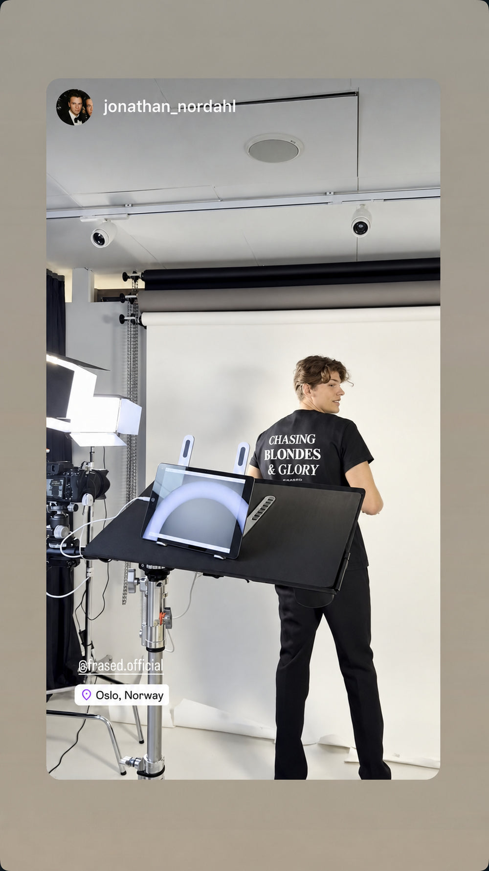 Model in a photo studio wearing a black FRASED T-shirt with “Chasing Blondes & Glory” on the back.