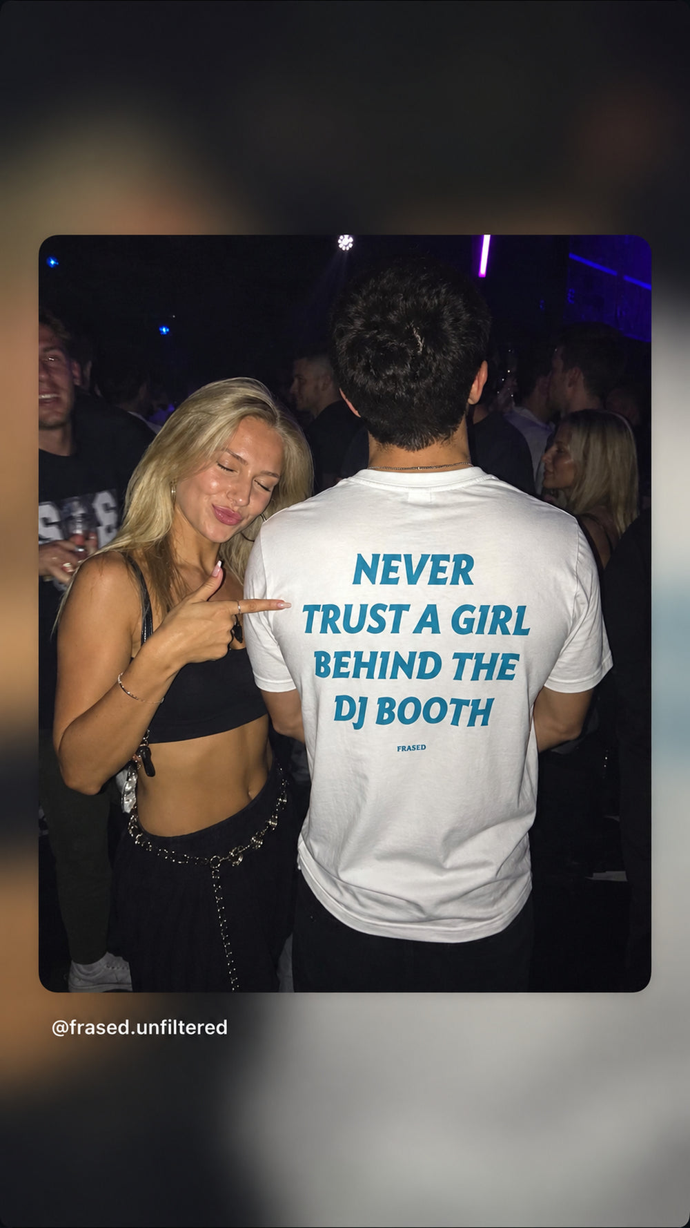 Kvinde peger på NEVER TRUST A GIRL BEHIND THE DJ BOOTH print på hvid T-shirt i klub