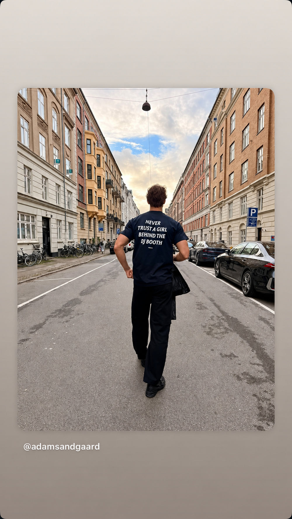 Person i sort NEVER TRUST A GIRL BEHIND THE DJ BOOTH T-shirt går ad bygade