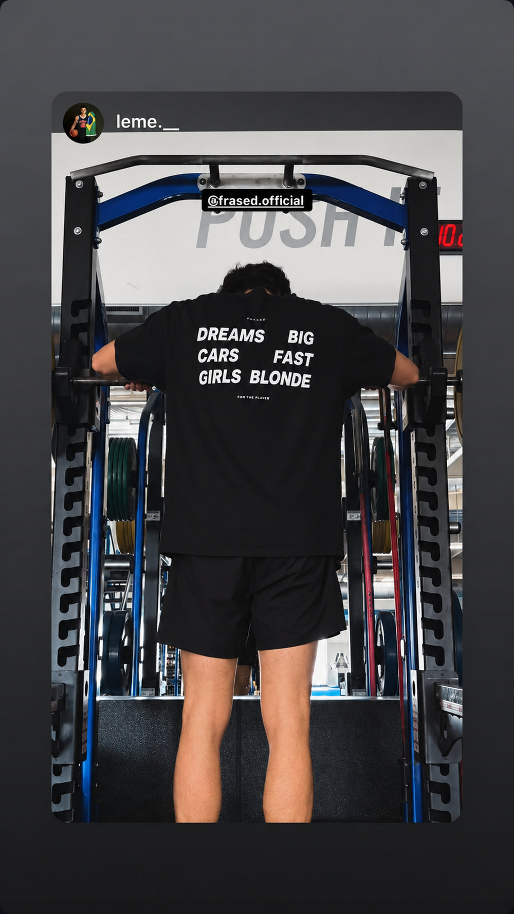 Person træner i sort FRASED T-shirt med 'Dreams Big. Cars Fast. Girls Blonde' på ryggen.