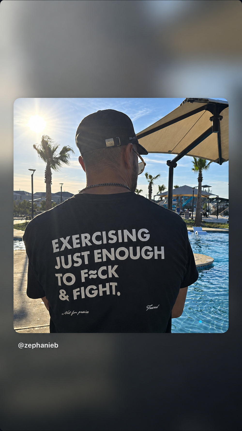 Man beside a swimming pool wearing a black “EXERCISING JUST ENOUGH TO F*CK & FIGHT” T-shirt.