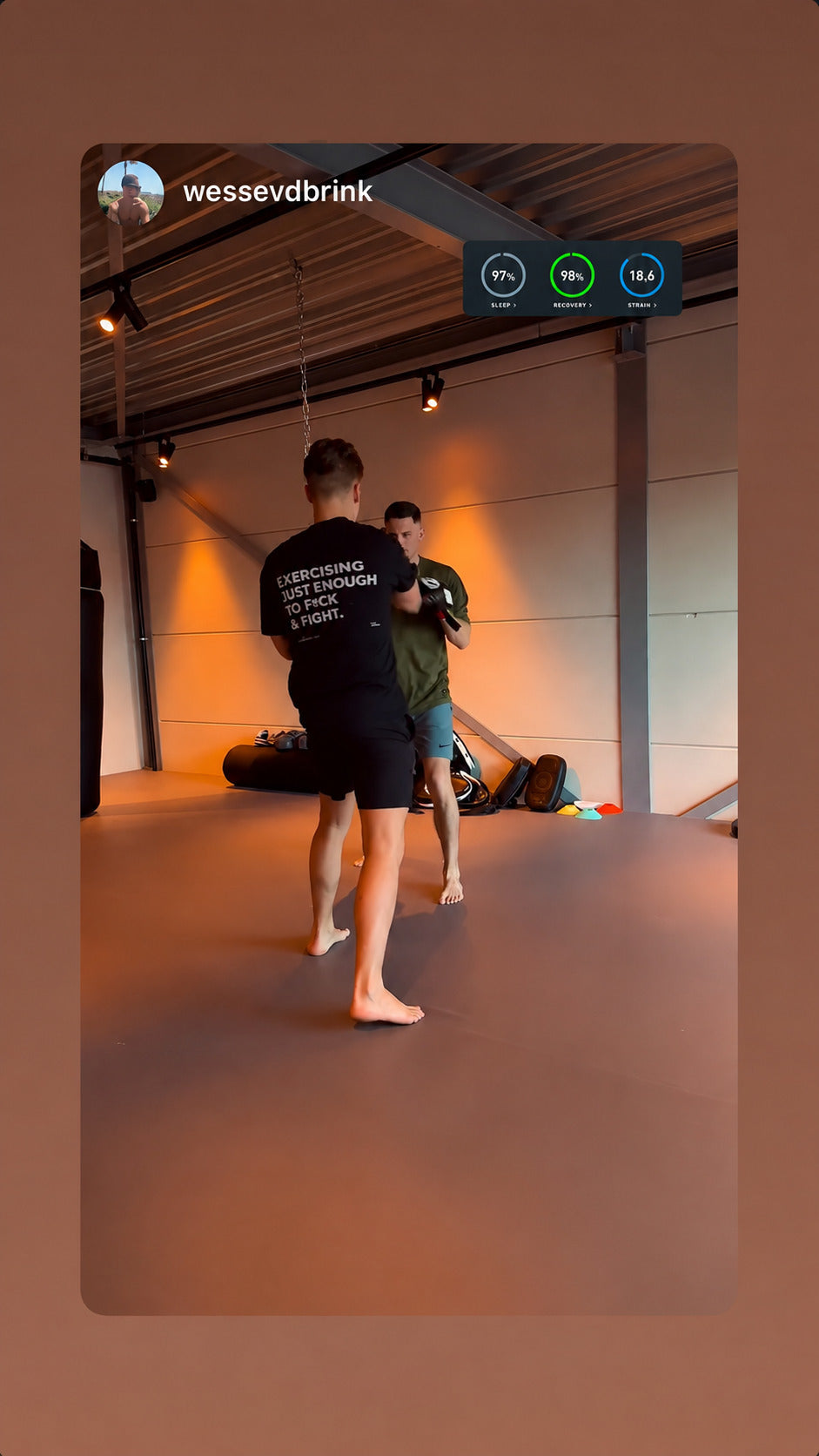 Two people sparring; one wears a black “EXERCISING JUST ENOUGH TO F*CK & FIGHT” T-shirt.