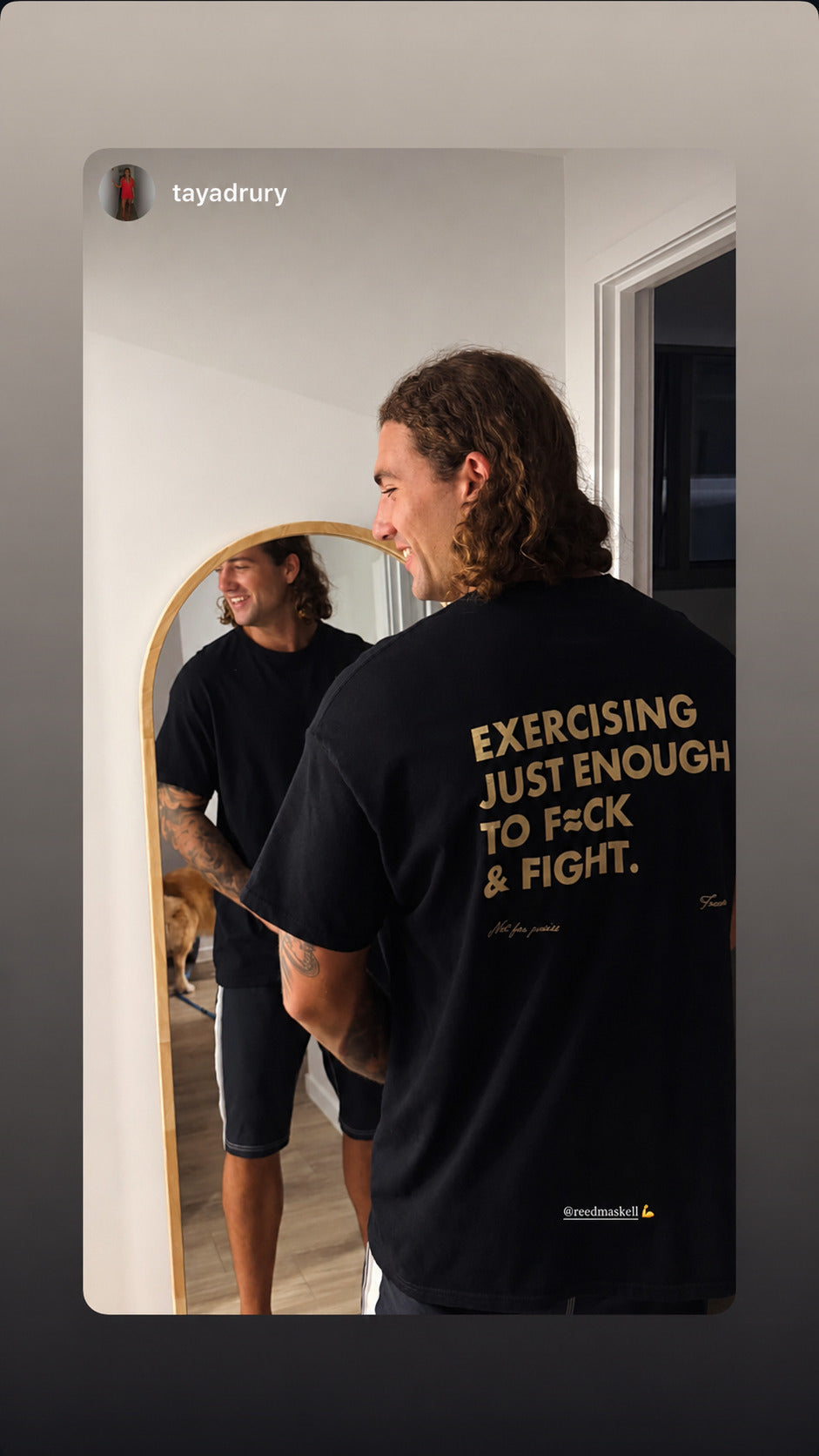 Man in a black “EXERCISING JUST ENOUGH TO F*CK & FIGHT” T-shirt in front of a mirror.