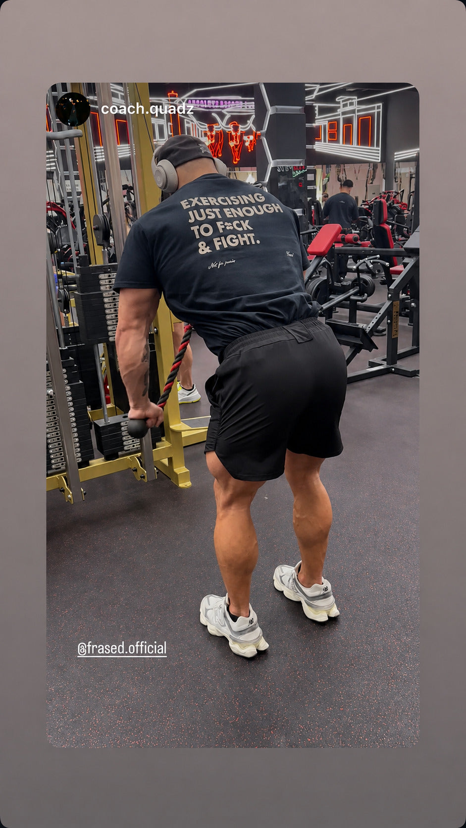 Man exercising on a cable machine in a black “EXERCISING JUST ENOUGH TO F*CK & FIGHT” T-shirt.