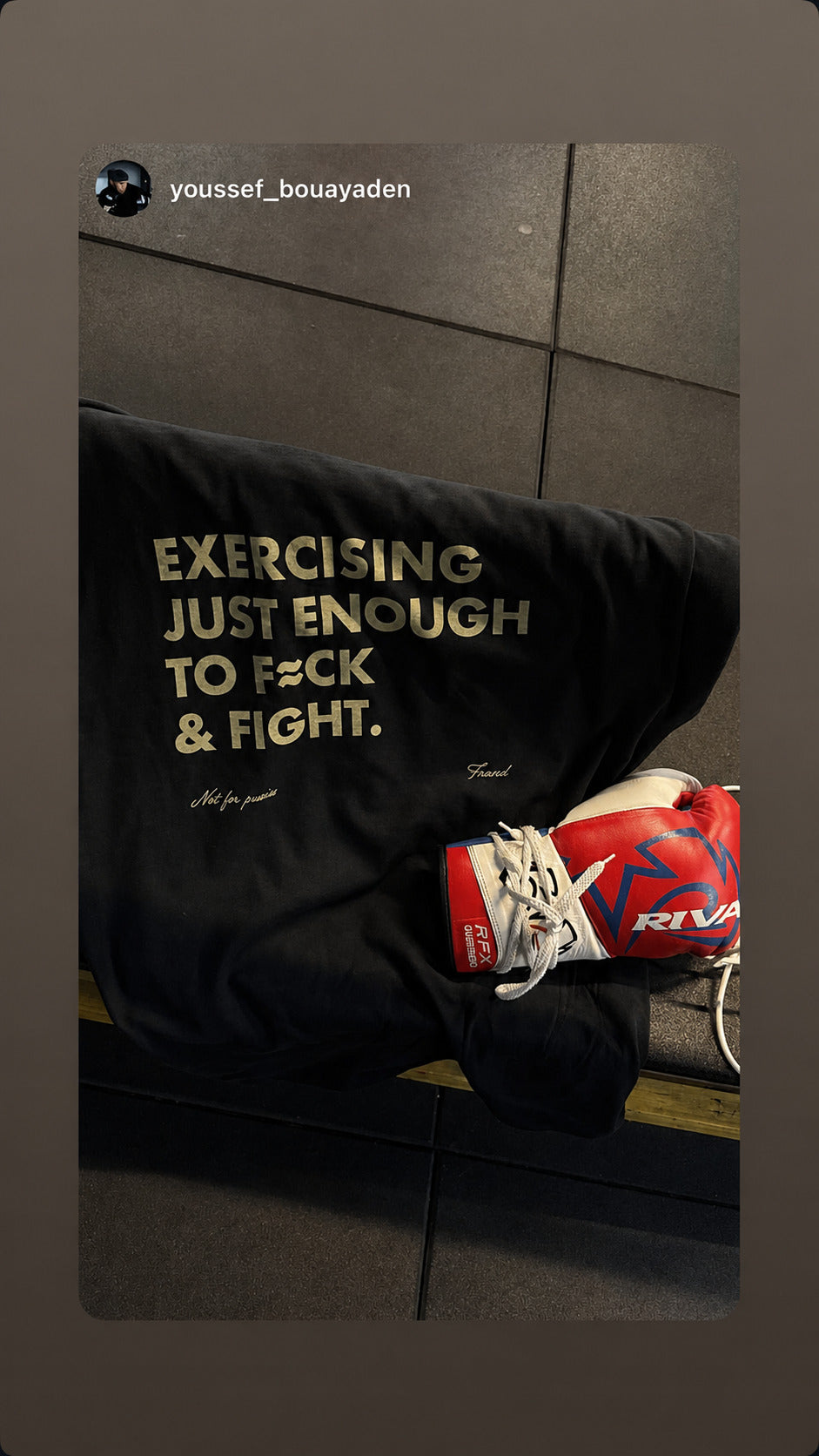 Black “EXERCISING JUST ENOUGH TO F*CK & FIGHT” T-shirt laid beside red boxing gloves.