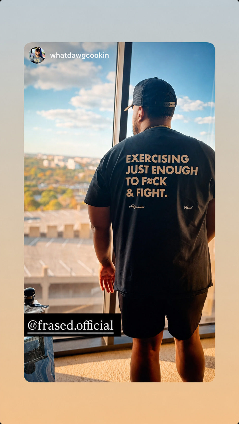 Man by a window overlooking the city in a black “EXERCISING JUST ENOUGH TO F*CK & FIGHT” T-shirt.
