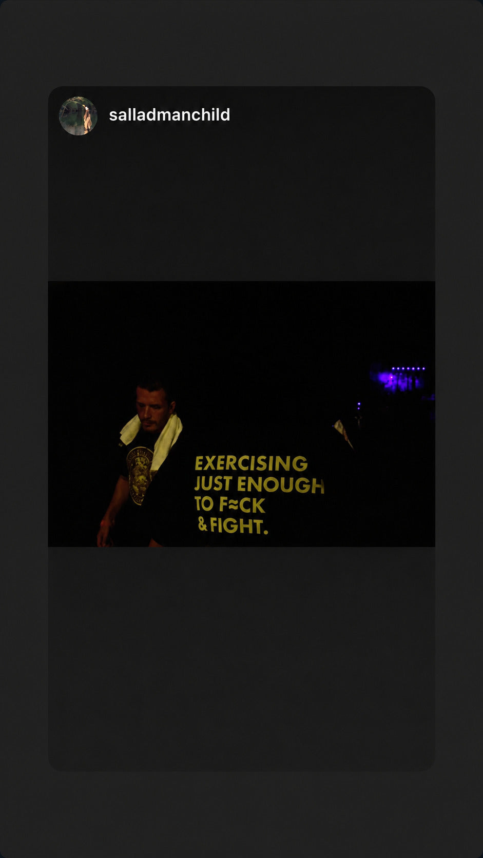 Black “EXERCISING JUST ENOUGH TO F*CK & FIGHT” T-shirt in a dark room.