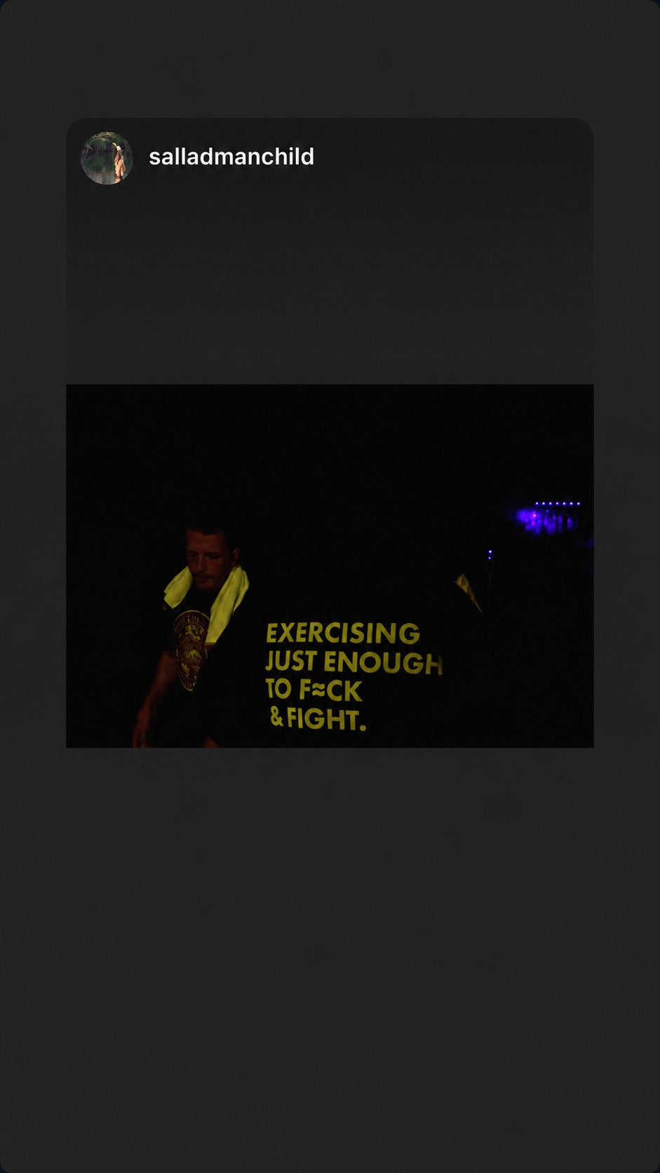 Black “EXERCISING JUST ENOUGH TO F*CK & FIGHT” T-shirt in a dark room.