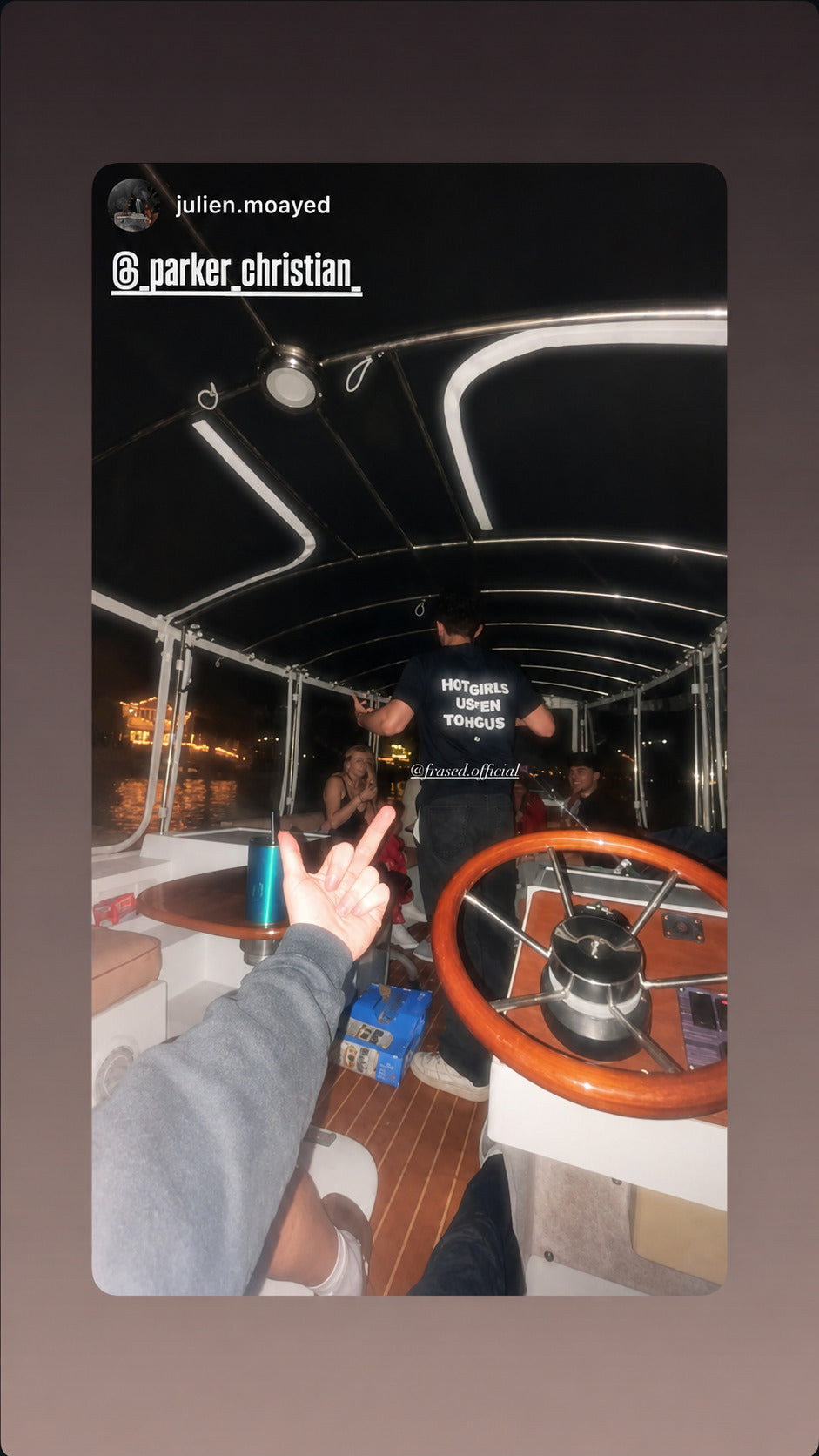 Person aboard a boat at night in a black “HOT GIRLS LISTEN TO HOUSE” T-shirt.
