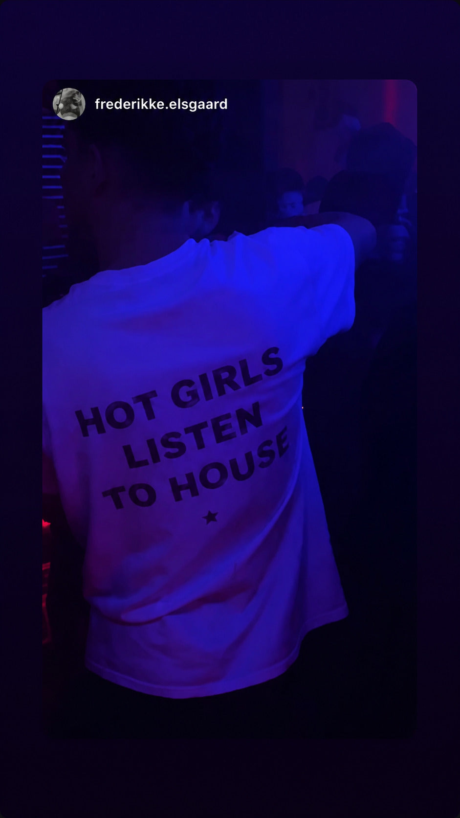 Person dancing under blue club lights in a white “HOT GIRLS LISTEN TO HOUSE” T-shirt.