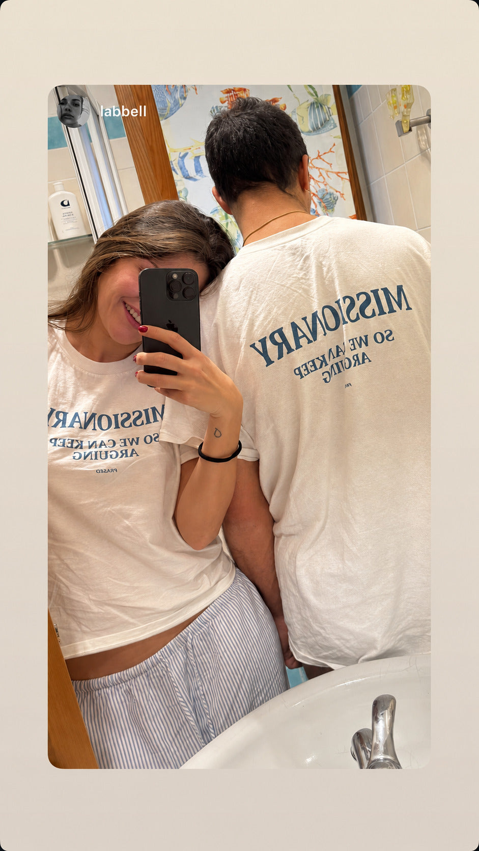 Mirror selfie of a couple in white FRASED T-shirts with “Missionary So We Can Keep Arguing” prints.