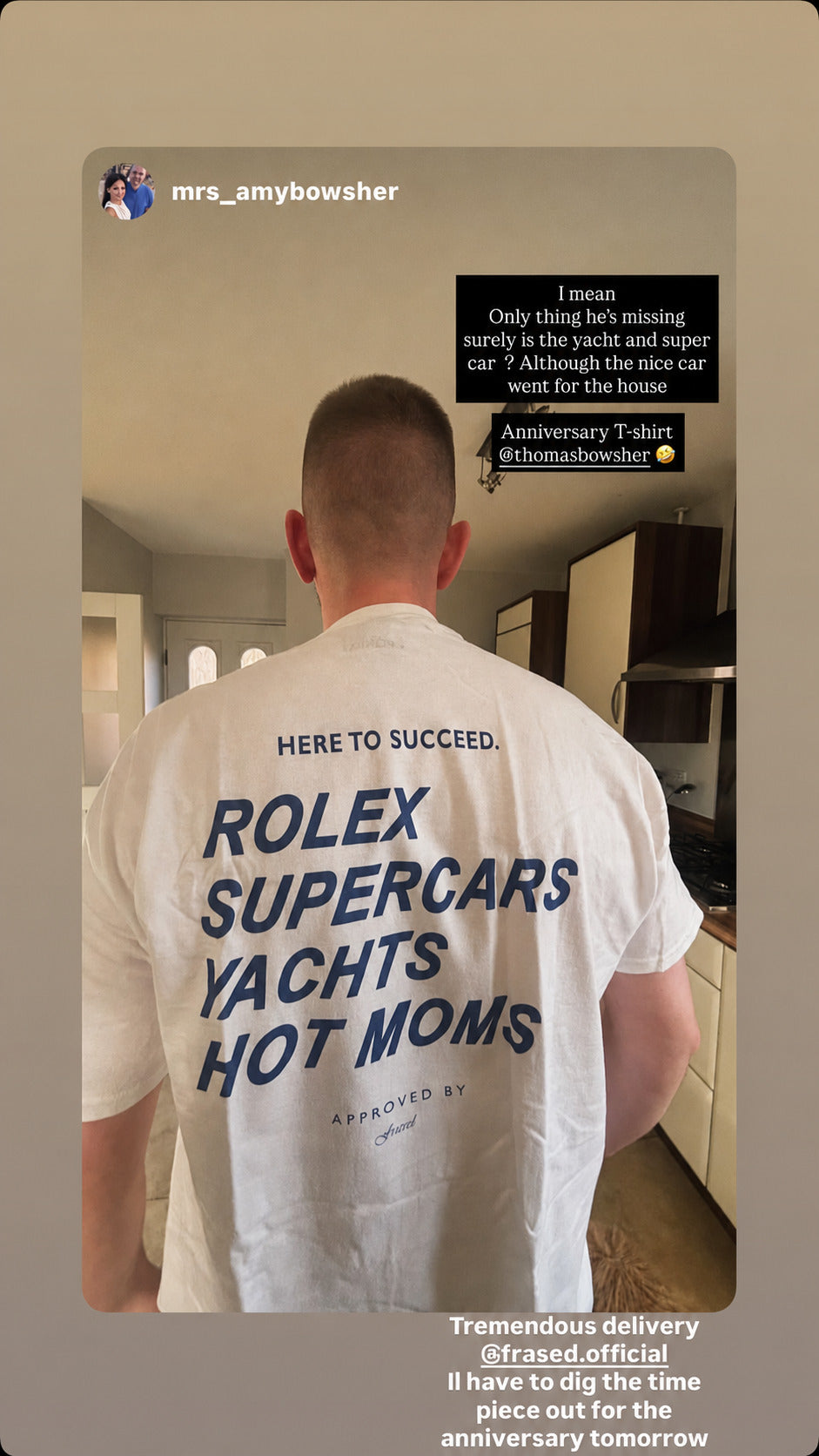 Mand i køkken iført hvid FRASED T-shirt med blåt 'Here to succeed. Rolex Supercars Yachts Hot Moms'-rygtryk.