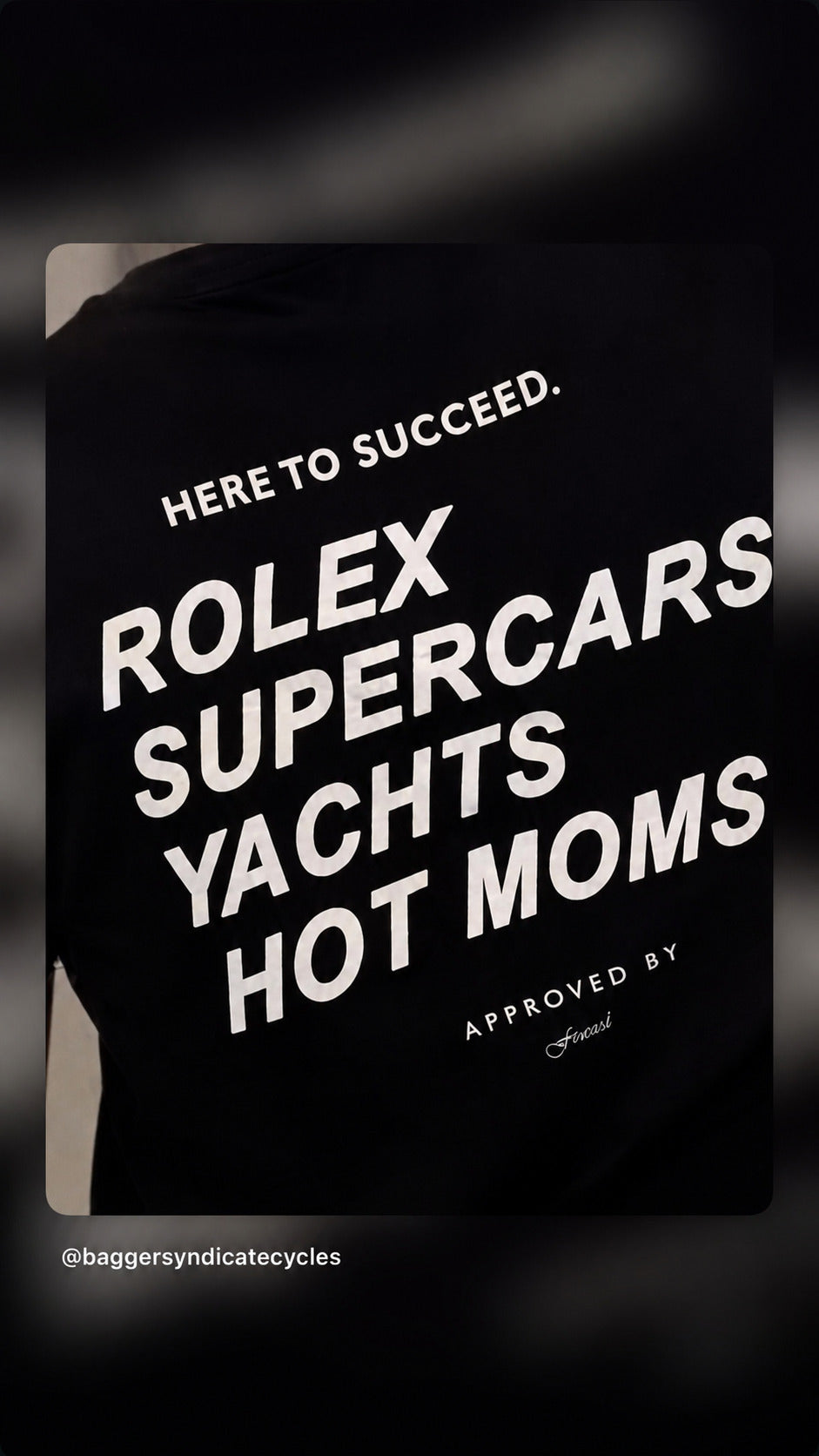 Nærbillede af sort FRASED T-shirt med hvidt 'Here to succeed. Rolex Supercars Yachts Hot Moms'-tryk.