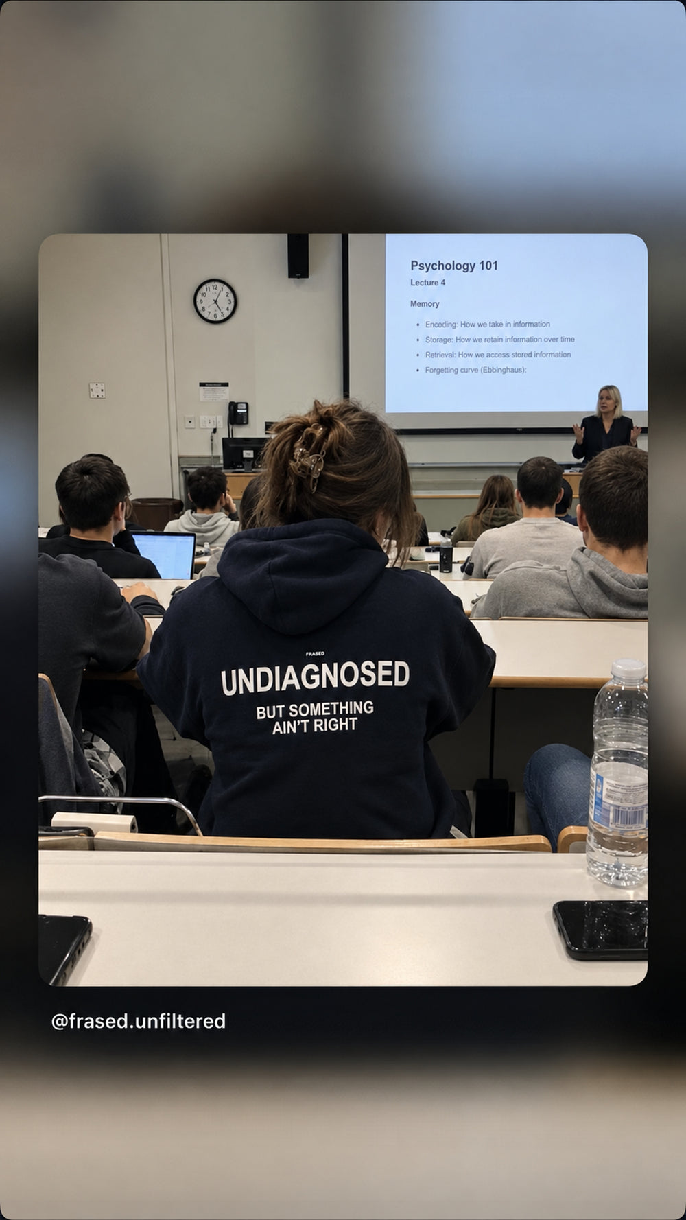 Person at a lecture in an auditorium wearing a dark “UNDIAGNOSED” hoodie.
