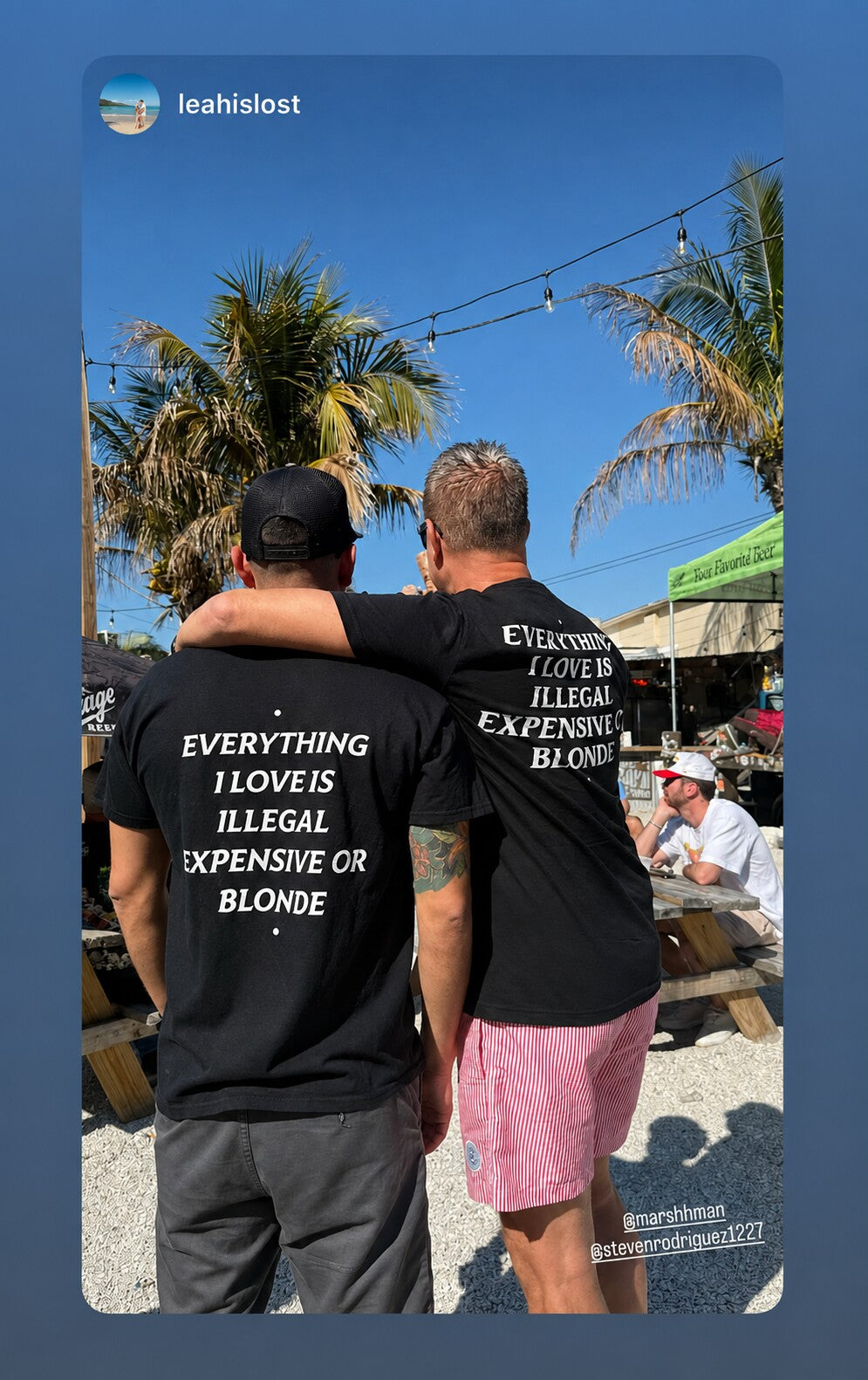 Two men outdoors wearing black “EVERYTHING I LOVE IS ILLEGAL EXPENSIVE OR BLONDE” T-shirts.