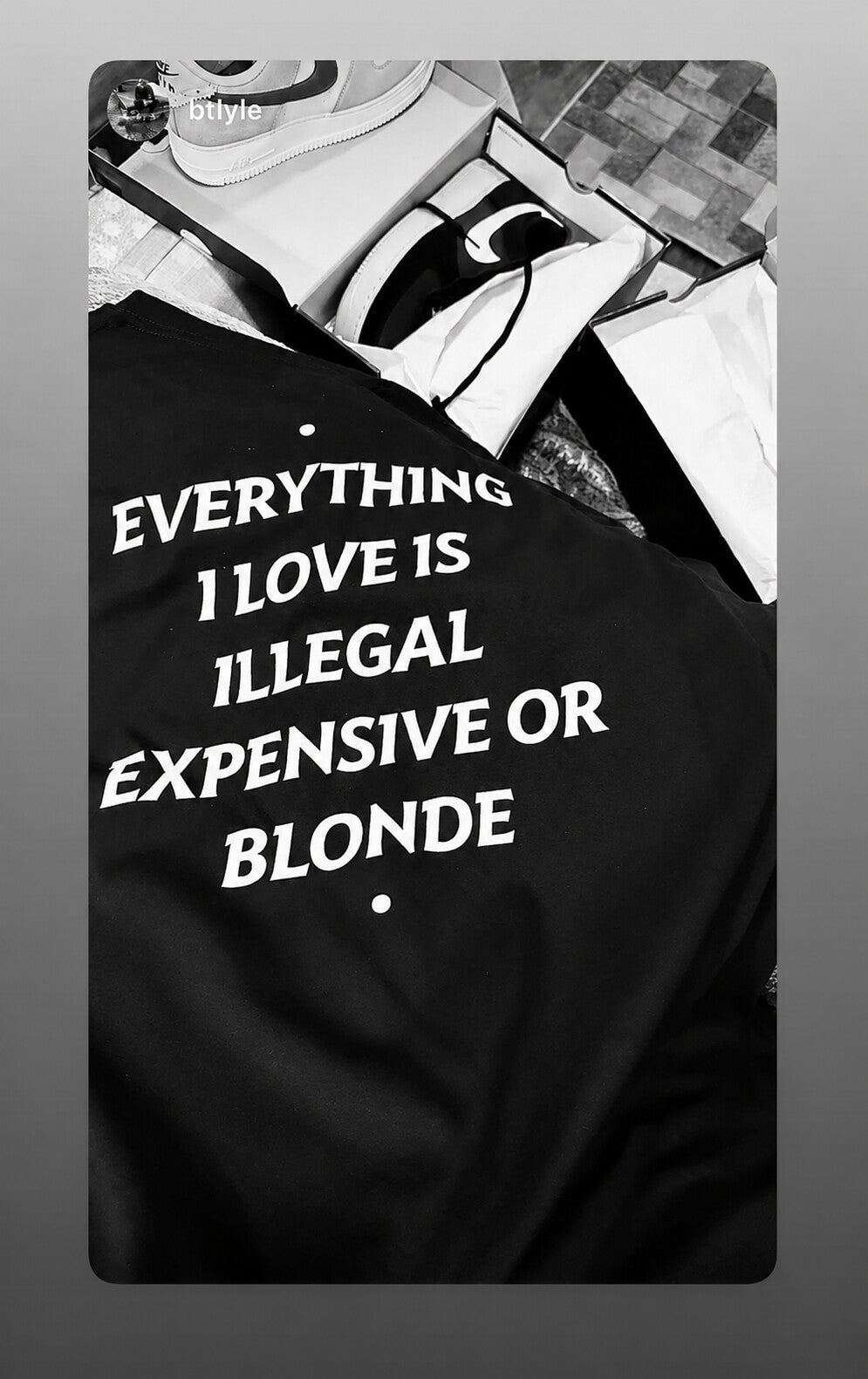 Black “EVERYTHING I LOVE IS ILLEGAL EXPENSIVE OR BLONDE” T-shirt beside shoe boxes.