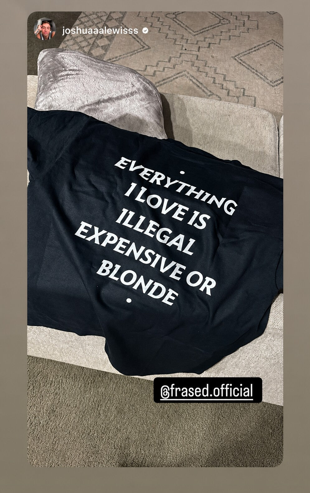 Black “EVERYTHING I LOVE IS ILLEGAL EXPENSIVE OR BLONDE” T-shirt laid on a sofa.