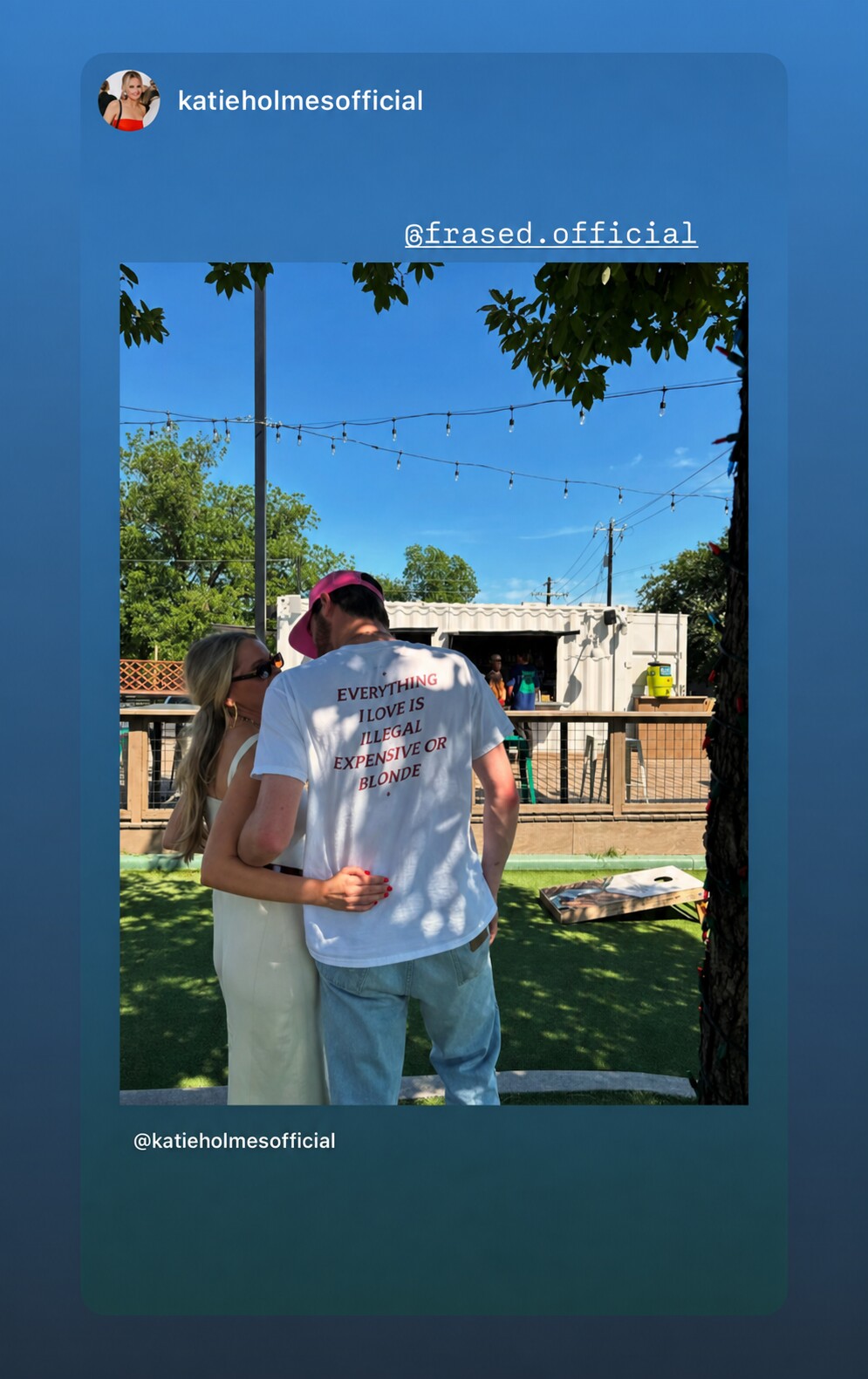 Couple in a garden; the man wears a white “EVERYTHING I LOVE IS ILLEGAL EXPENSIVE OR BLONDE” T-shirt.