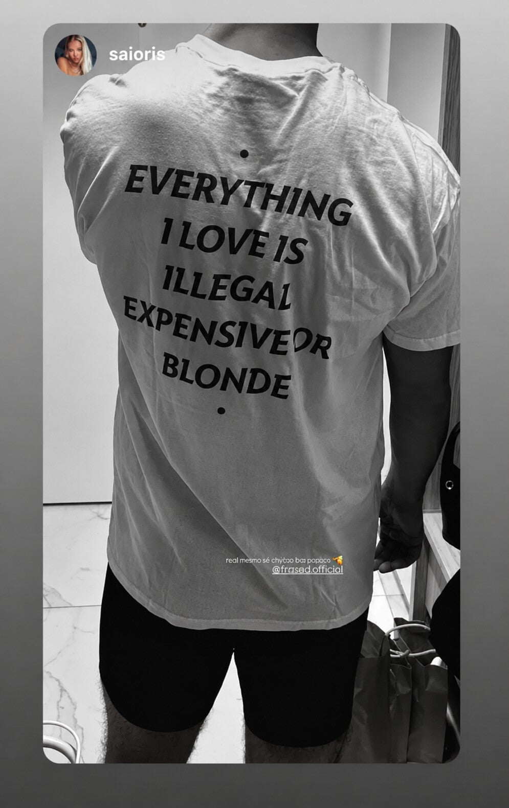Black-and-white close-up of a white “EVERYTHING I LOVE IS ILLEGAL EXPENSIVE OR BLONDE” T-shirt.