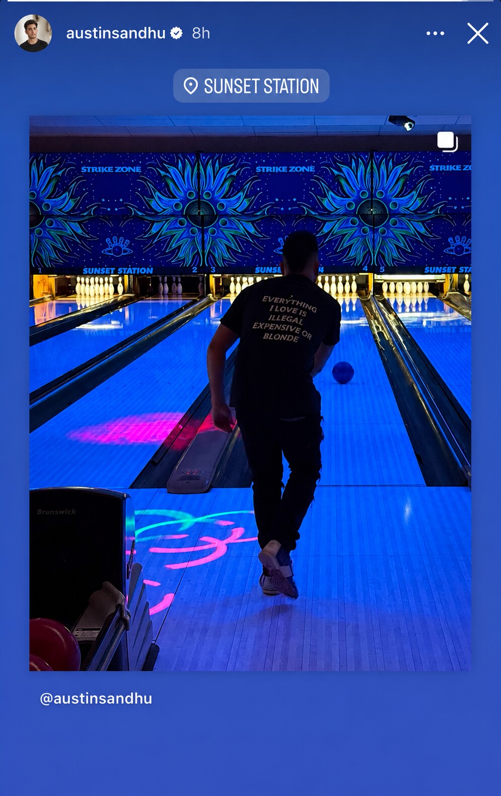 Man bowling under blue lights in a black “EVERYTHING I LOVE IS ILLEGAL EXPENSIVE OR BLONDE” T-shirt.