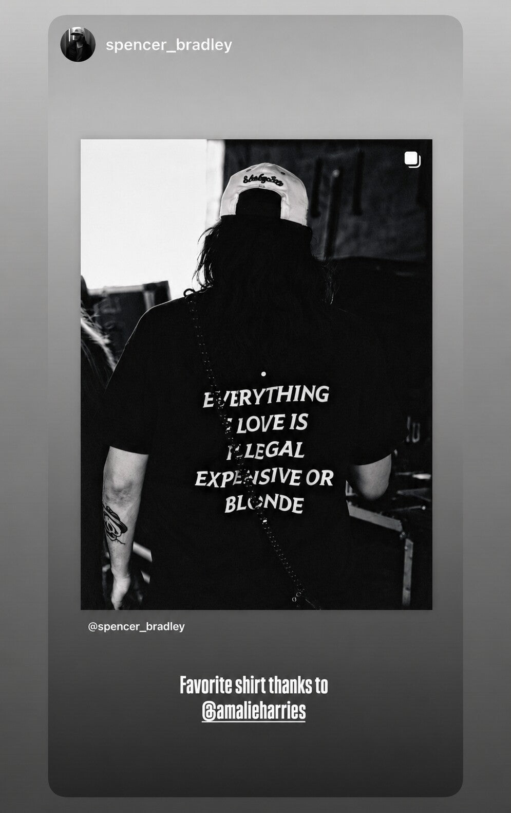 Black-and-white photo of a person in a black “EVERYTHING I LOVE IS ILLEGAL EXPENSIVE OR BLONDE” T-shirt.