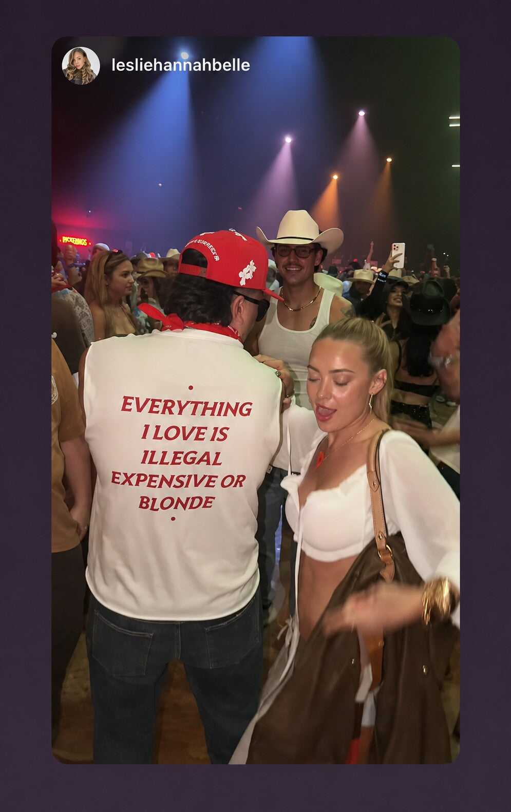Man at a party wearing a white “EVERYTHING I LOVE IS ILLEGAL EXPENSIVE OR BLONDE” T-shirt.