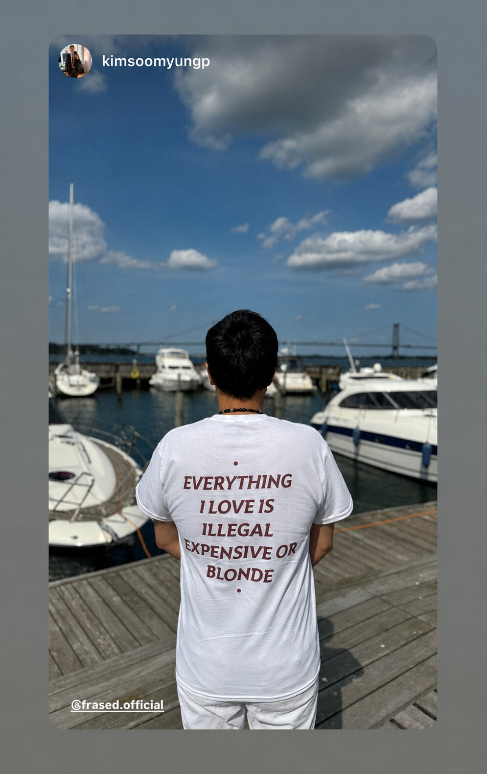 Person on a boat dock in a white “EVERYTHING I LOVE IS ILLEGAL EXPENSIVE OR BLONDE” T-shirt.